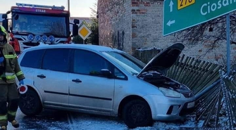 Kierowca forda wpadł w płot i znak drogowy.